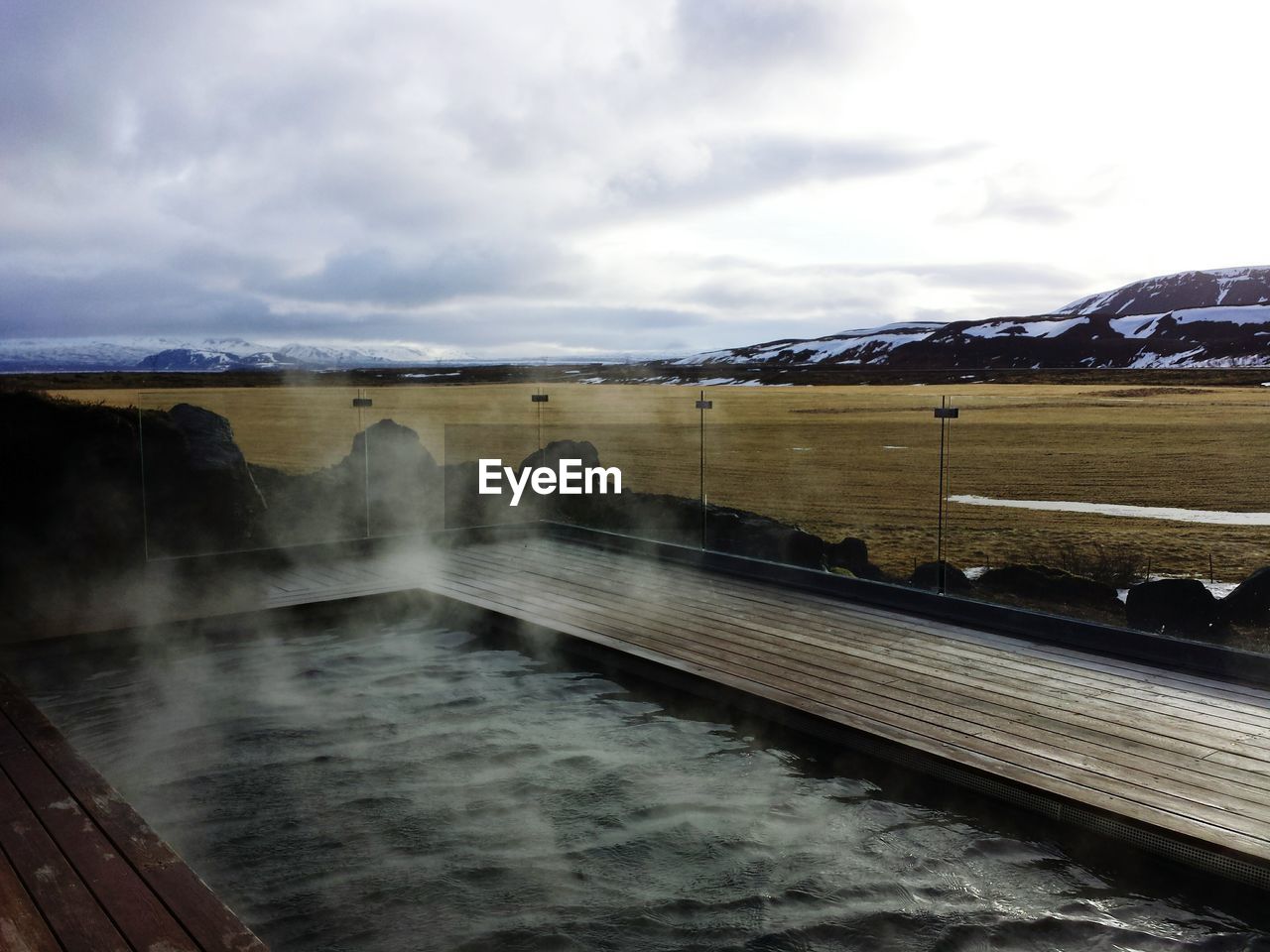 SCENIC VIEW OF SEA AND MOUNTAINS AGAINST CLOUDY SKY