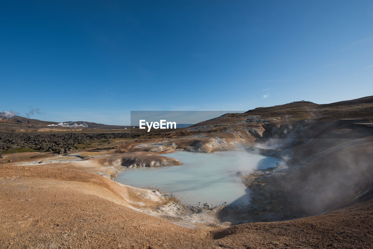 Scenic view of hot spring against blue sky