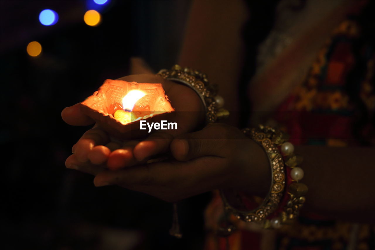 Midsection of woman holding lit diya