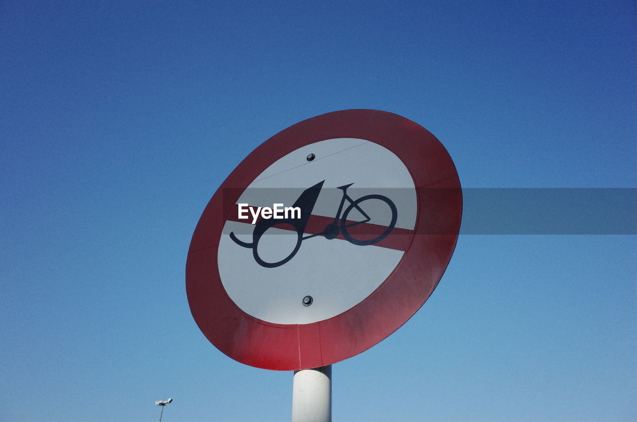 Low angle view of road sign against clear blue sky