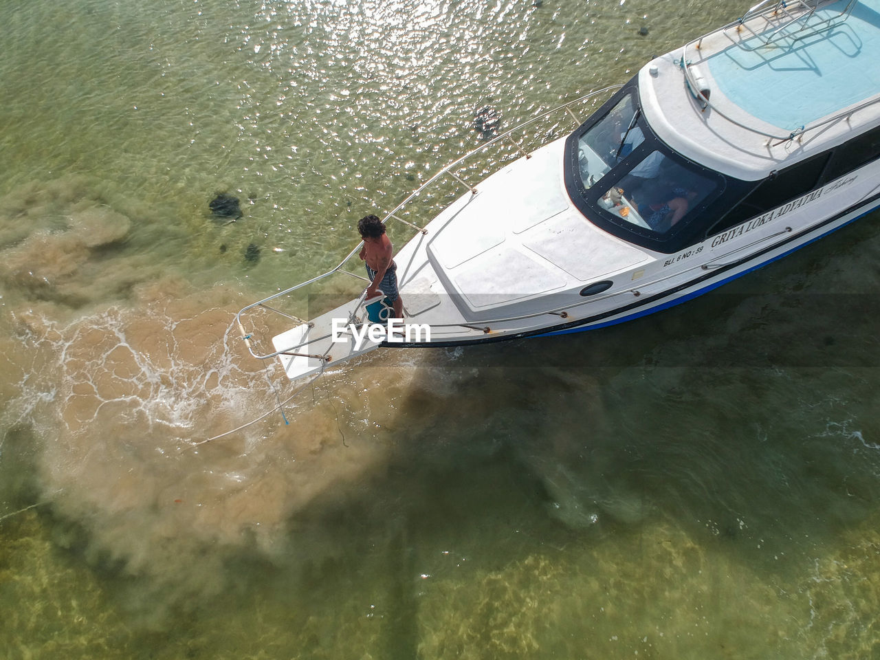 HIGH ANGLE VIEW OF MAN IN BOAT AT SEA