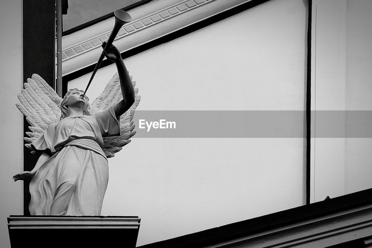 REAR VIEW OF WOMAN HOLDING UMBRELLA AGAINST BUILDING