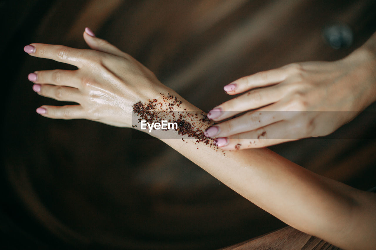 Woman applying coffee natural body scrub on hand