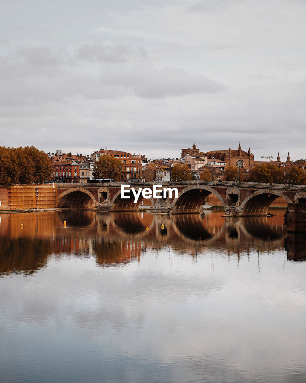 Bridge over river by buildings against sky