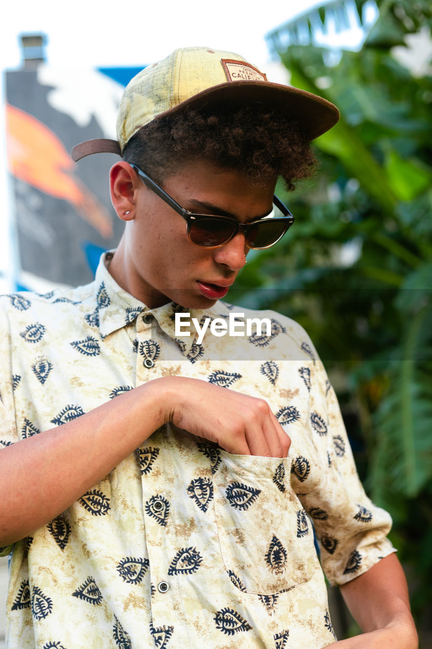 A young man checking o tshirt pocket wearing sunglasses