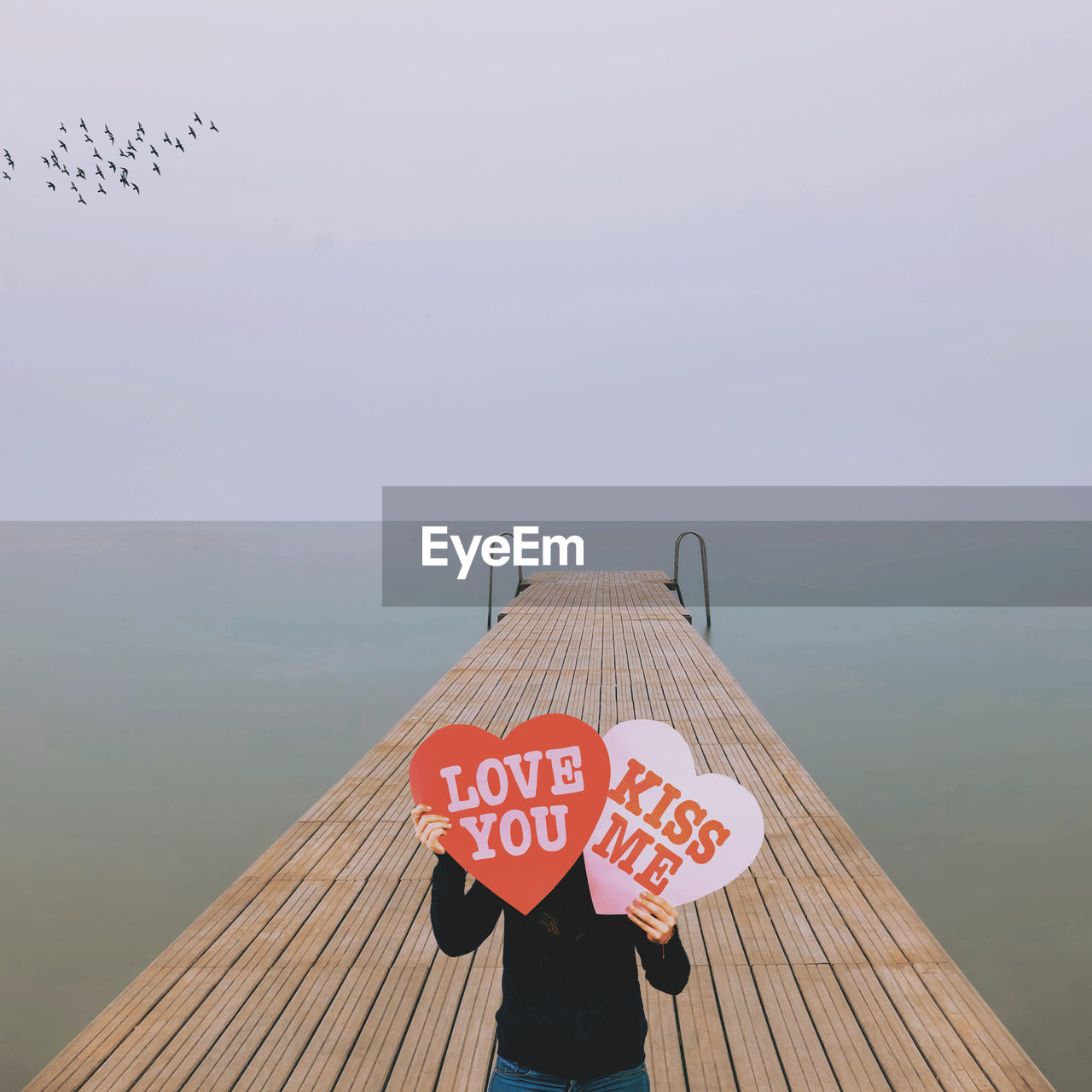 High angle view of woman holing heart shape with text while standing on pier