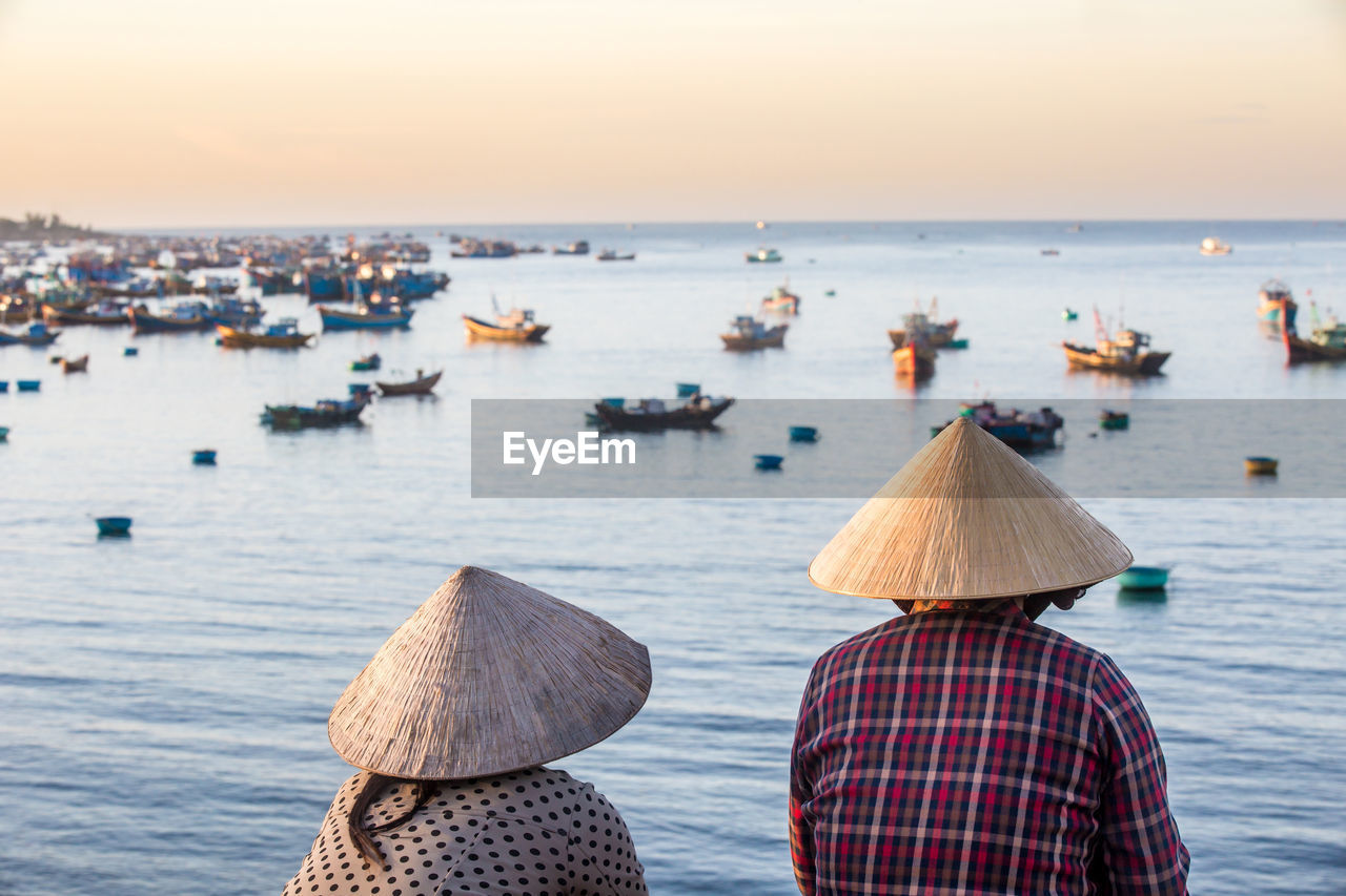 Unidentified vietnamese women overlooking fishermans bay full of fishing boats.