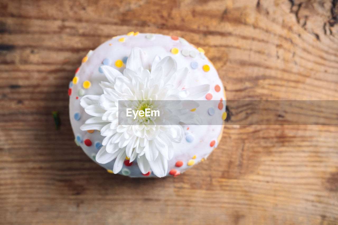 Chrysanthemum bud on top of donut on wooden background. 