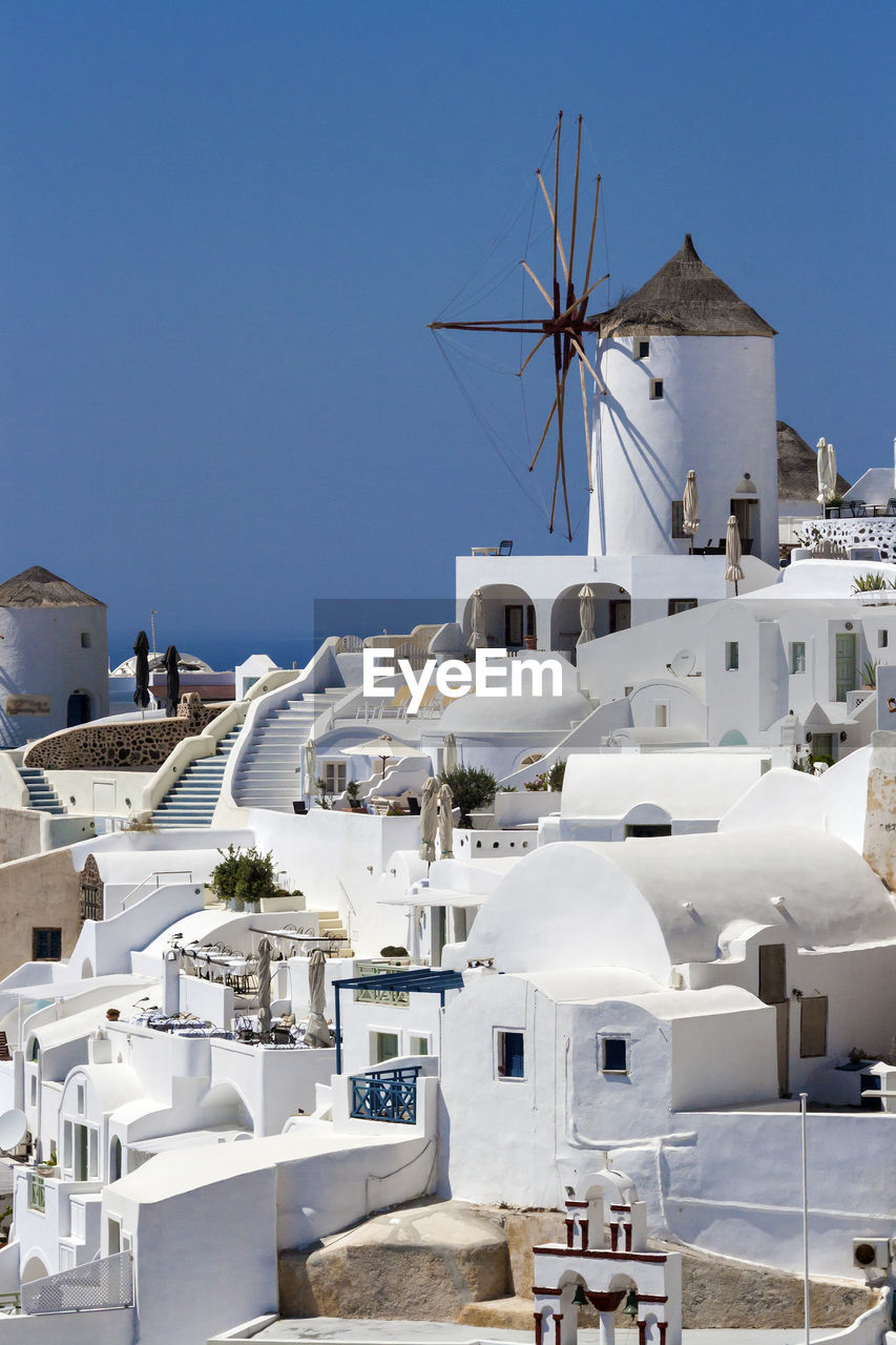 Traditional windmill by buildings against sky