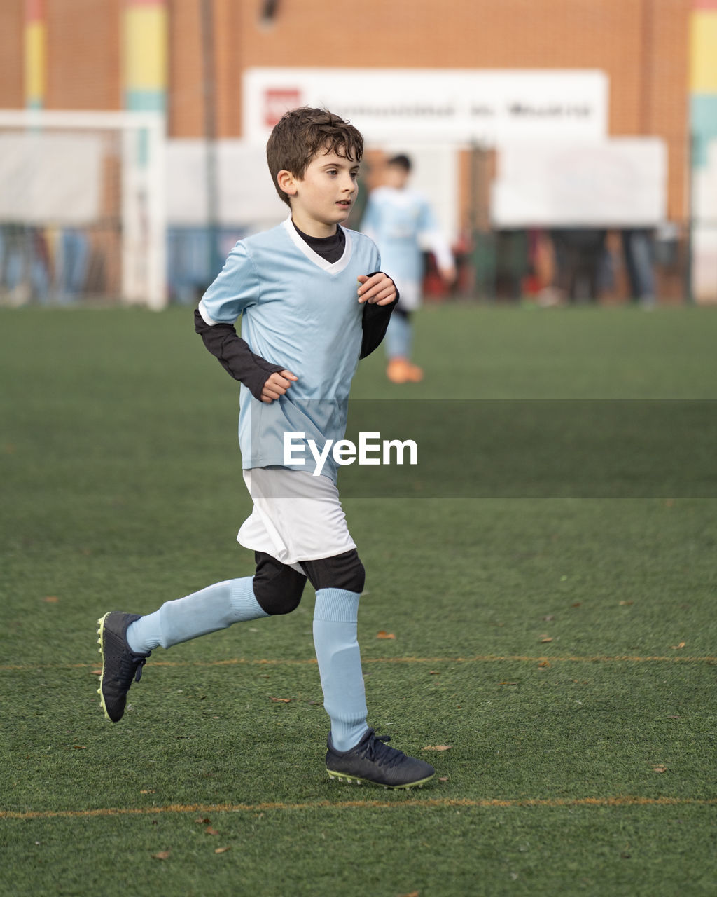 Portrait of young boy play on the grass football field in the stadium during a match in cold weather