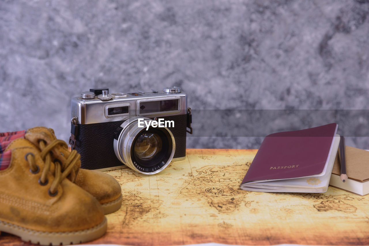 Close-up of camera with passport and shoes on table