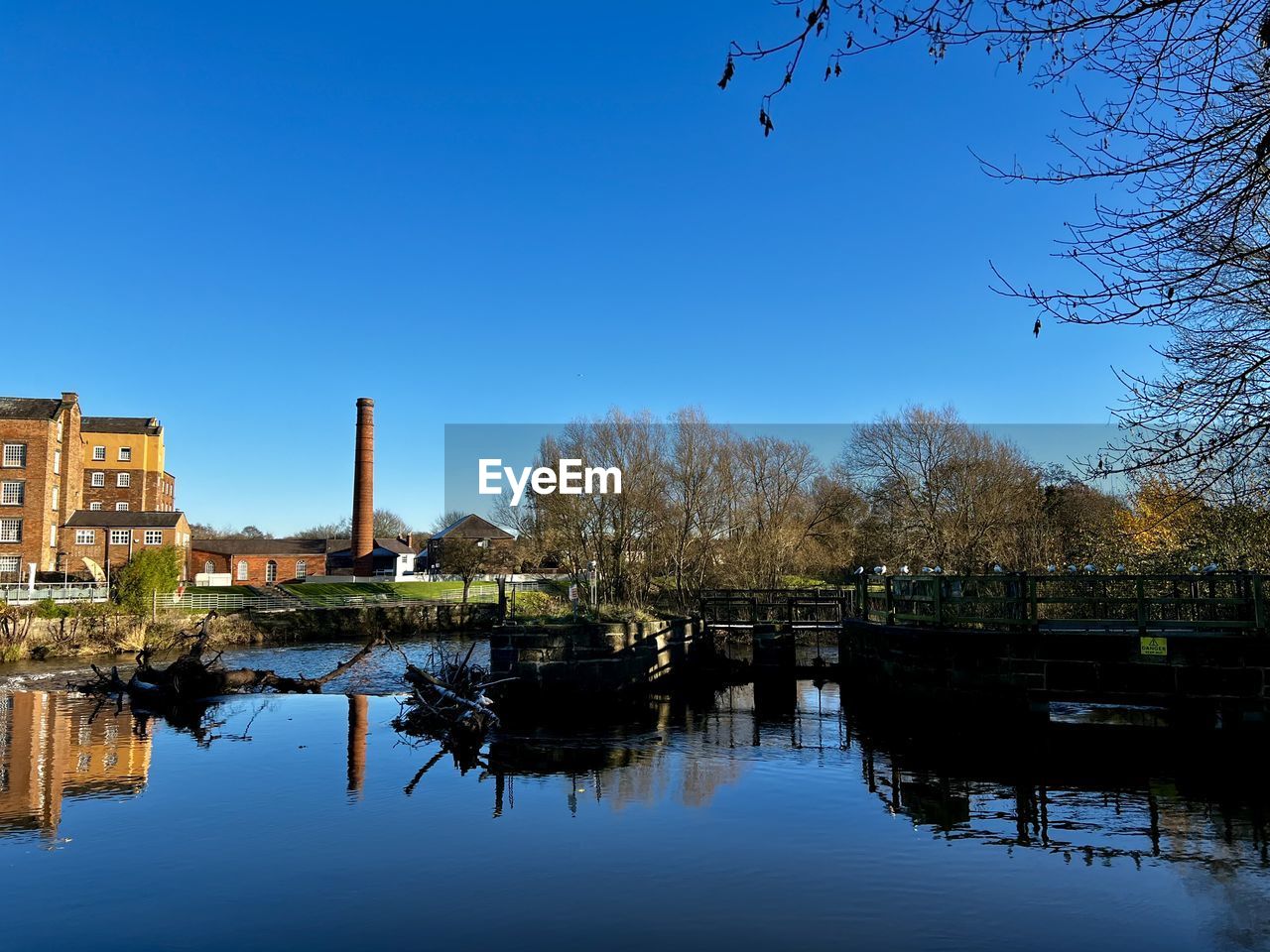 reflection, water, evening, sky, architecture, tree, river, dusk, built structure, nature, building exterior, waterway, cityscape, clear sky, plant, blue, no people, building, travel destinations, history, outdoors, city, autumn, waterfront, the past, day, urban area, body of water
