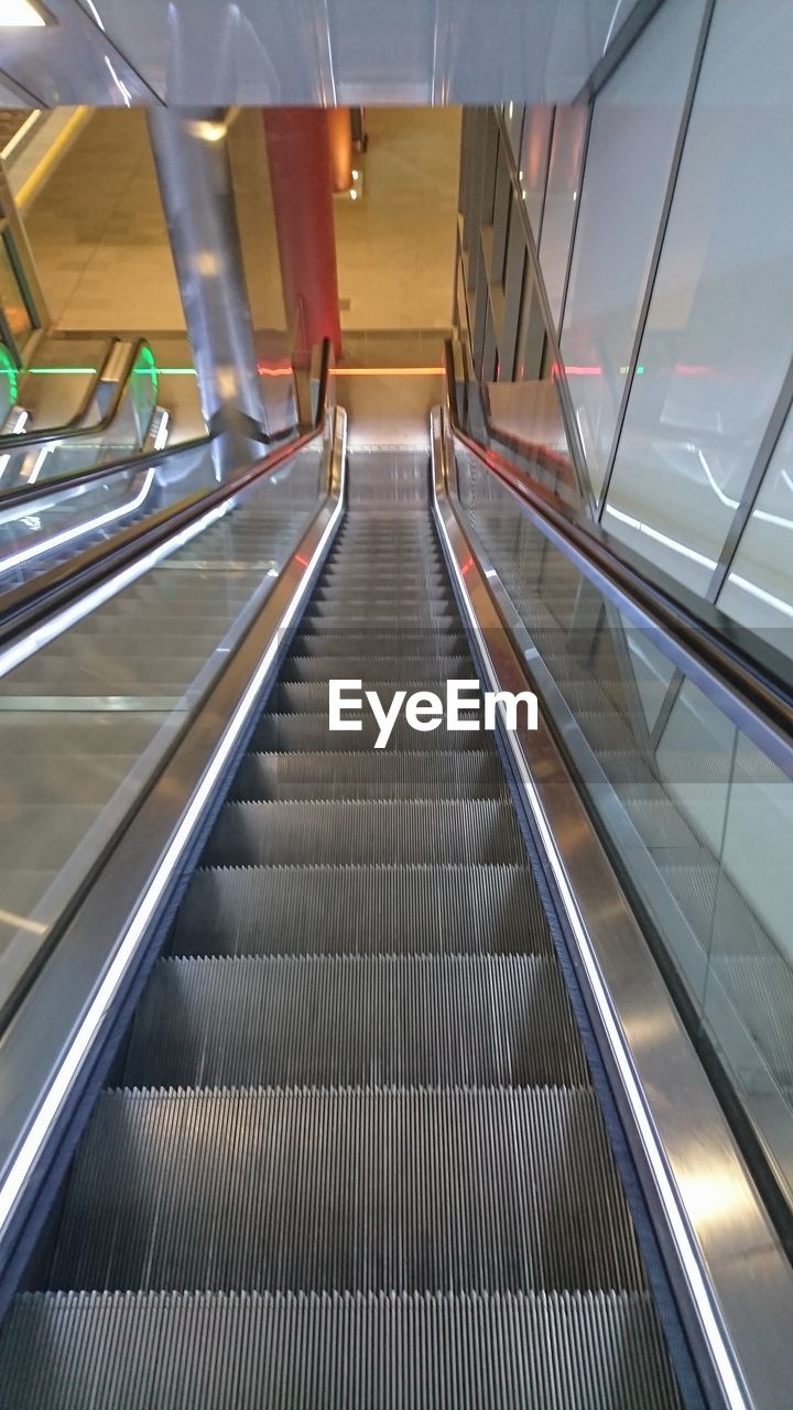 HIGH ANGLE VIEW OF ESCALATOR IN ILLUMINATED STAIRCASE
