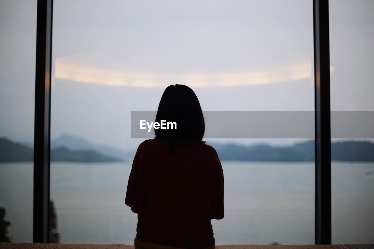 Rear view of silhouette woman against sea and sky