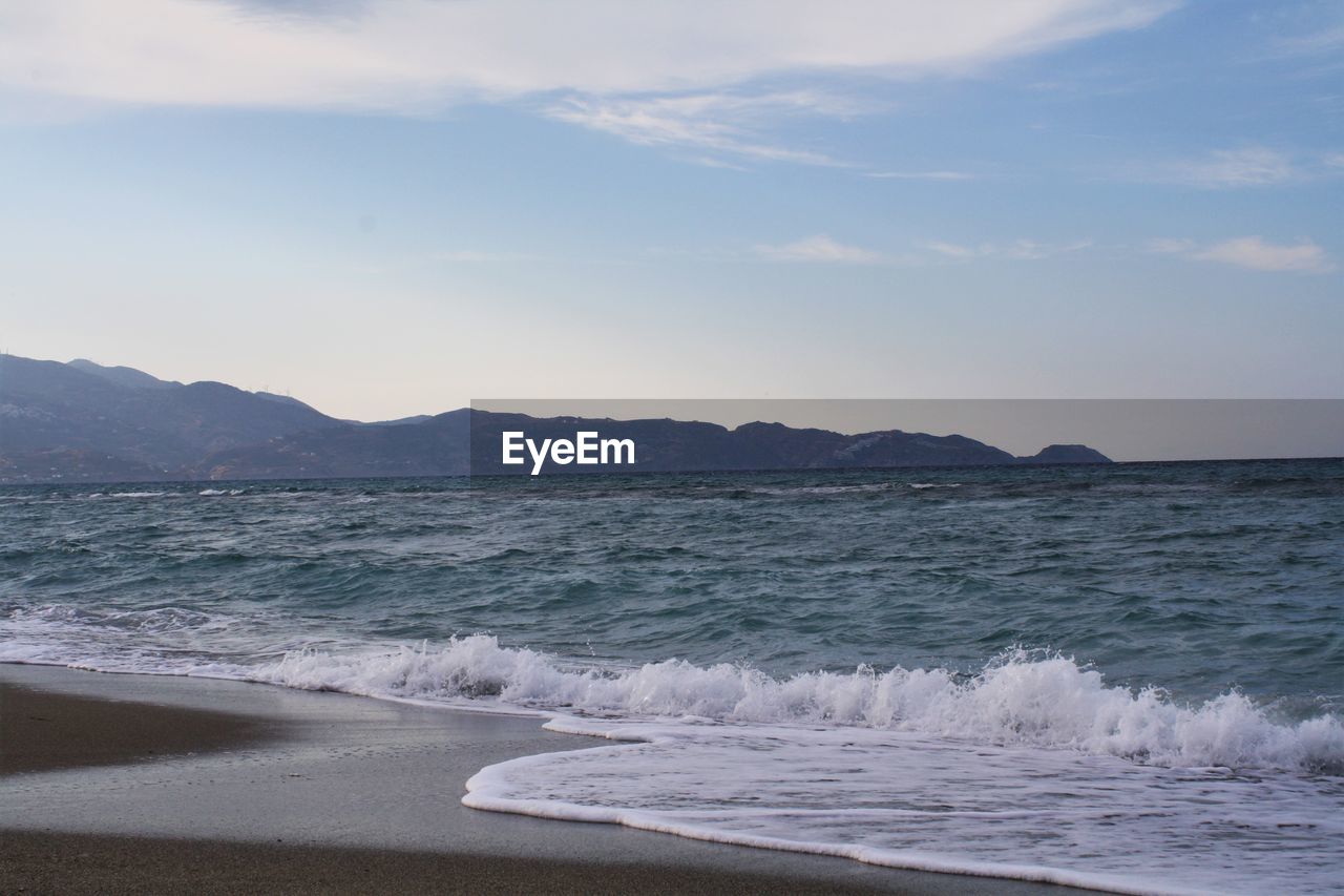 View of calm beach against mountain range