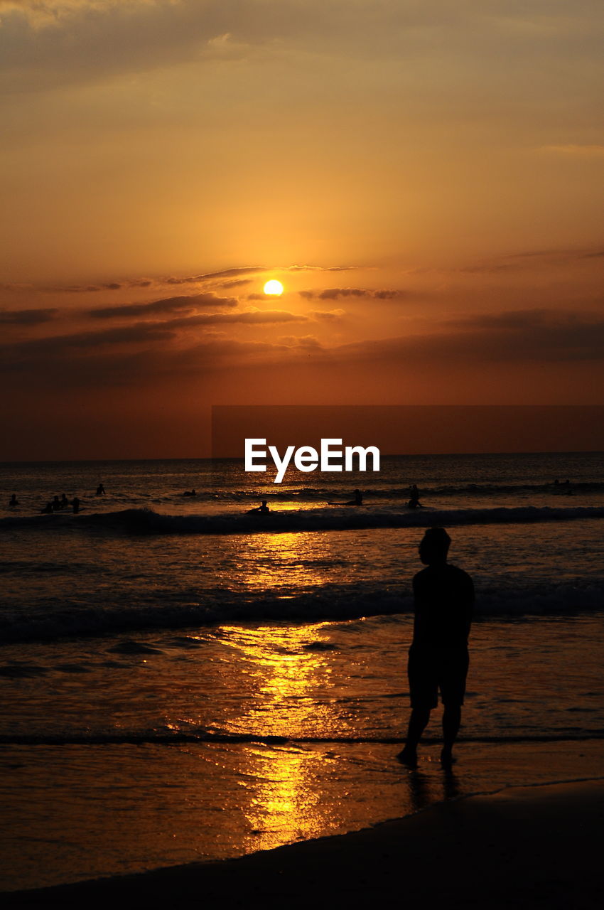 Silhouette man standing on beach during sunset