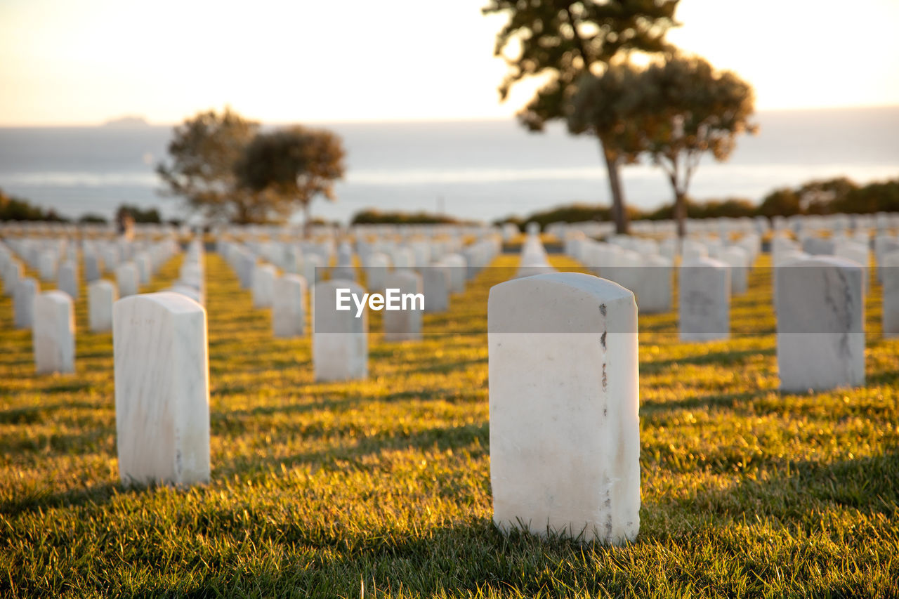 Cemetery on field against sky at sunset