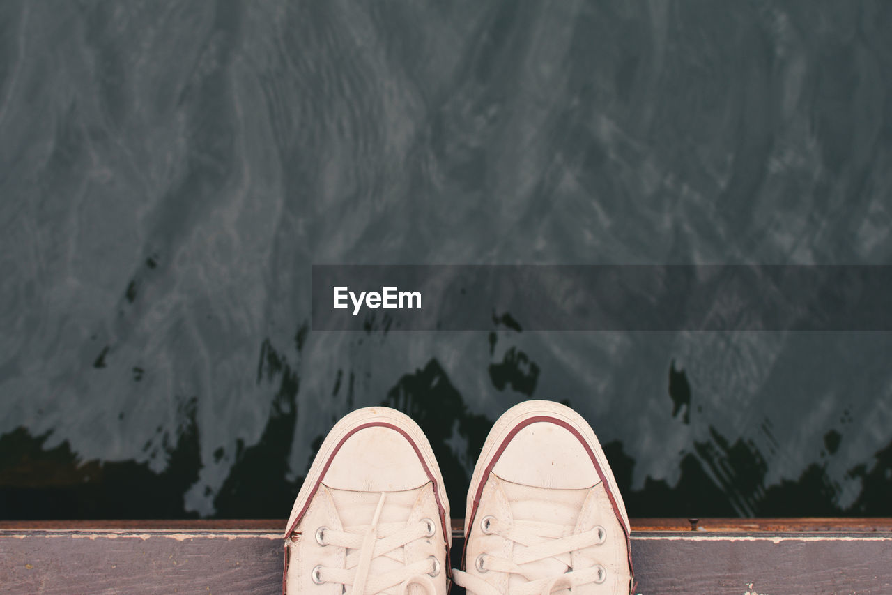 Low section of person standing on jetty over lake