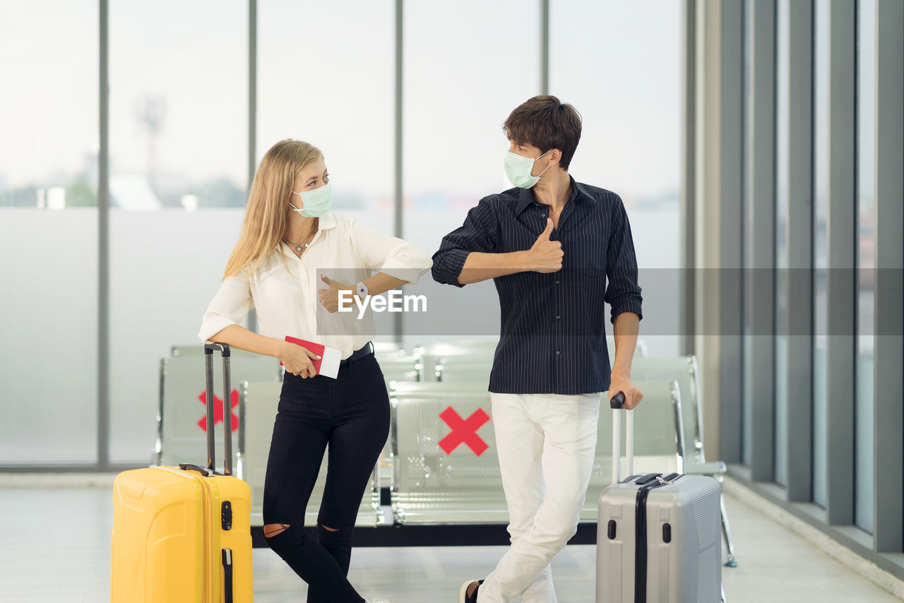 Life during covid-19 pandemic. young man and woman waiting for flying at airport at window 