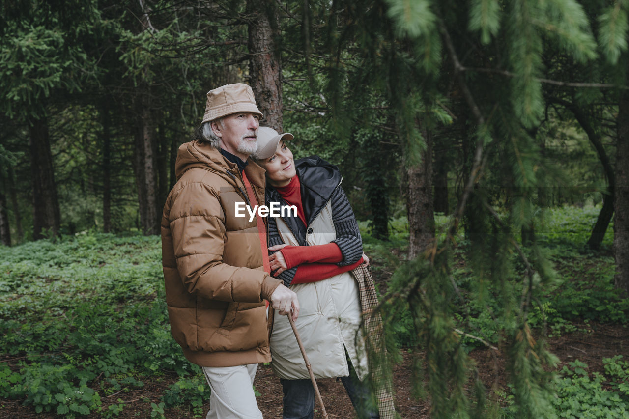 Thoughtful couple standing in forest