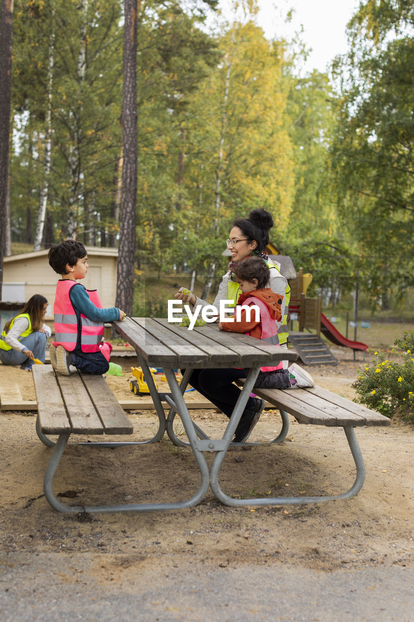 Preschool teacher and students eating grapes outdoors