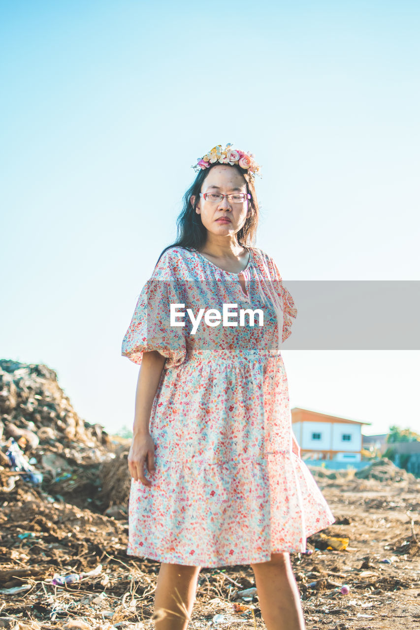one person, standing, women, spring, dress, clothing, nature, sky, adult, fashion, smiling, happiness, day, clear sky, portrait, photo shoot, emotion, blue, front view, leisure activity, copy space, casual clothing, land, full length, looking at camera, hairstyle, sunlight, pattern, young adult, outdoors, sunny, female, glasses, looking, carefree, lifestyles, hat, three quarter length, holiday, vacation, trip, summer, person, enjoyment, fun, brown hair, travel, child, floral pattern, landscape, cheerful, teeth, sunglasses, long hair