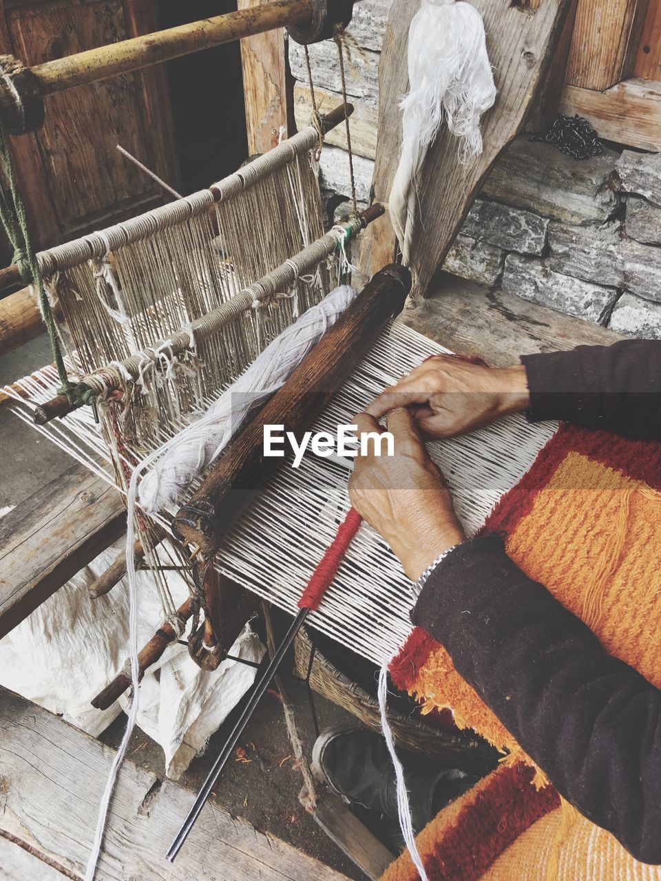 Cropped hands weaving loom in factory