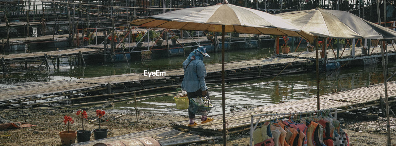 Rear view of man carrying baskets on boardwalk