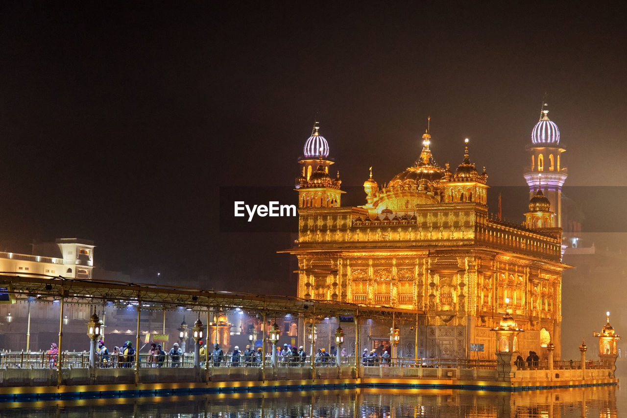 Illuminated buildings in city at night, golden temple amritsar 
