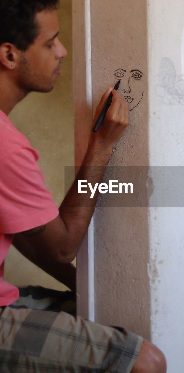 Man drawing face on wall