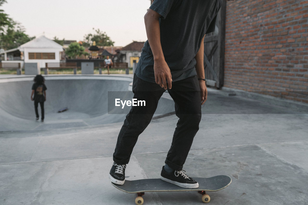 Low section of man skateboarding in city