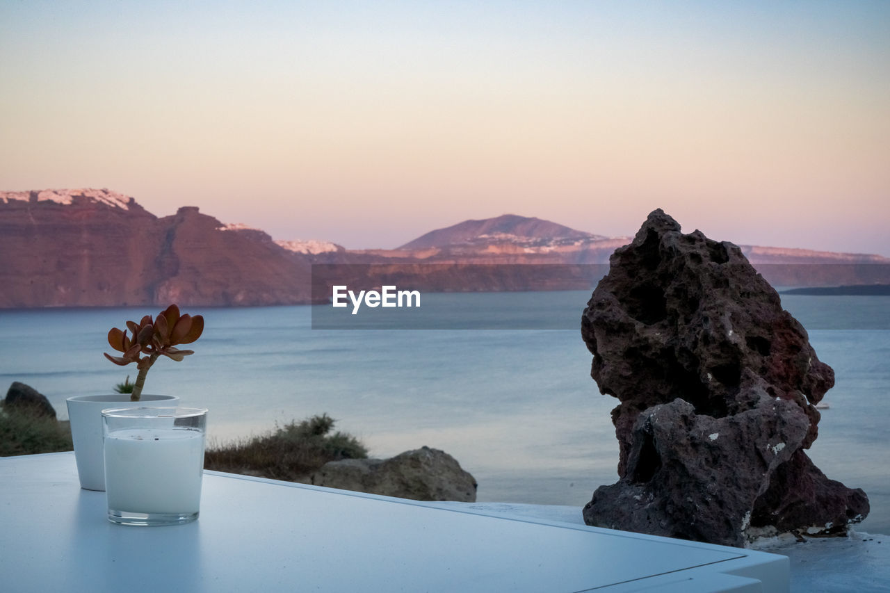 Candle and plant decoration on a white table. oia, santorini island. beautiful colors on caldera