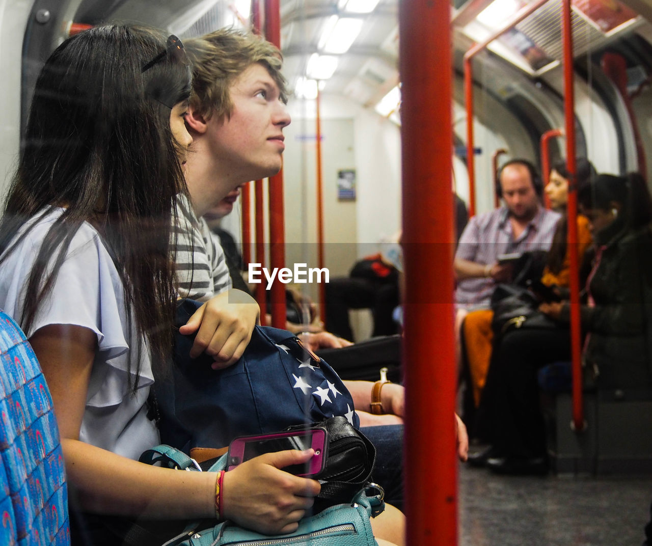 YOUNG WOMAN USING PHONE WHILE SITTING IN TRAIN