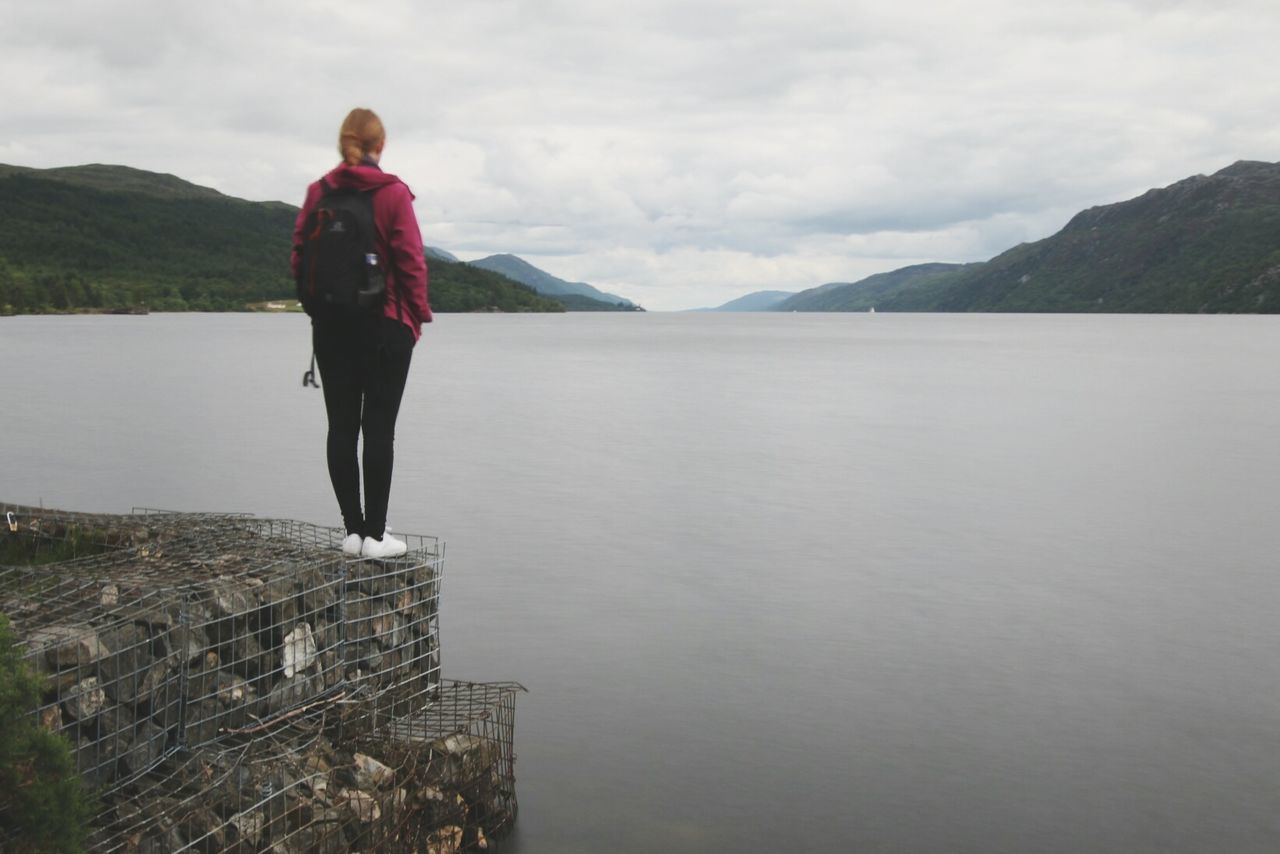 Rear view of woman standing on rocks by river