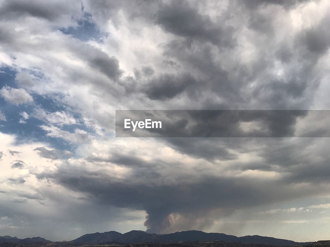 LOW ANGLE VIEW OF STORM CLOUDS OVER MOUNTAIN