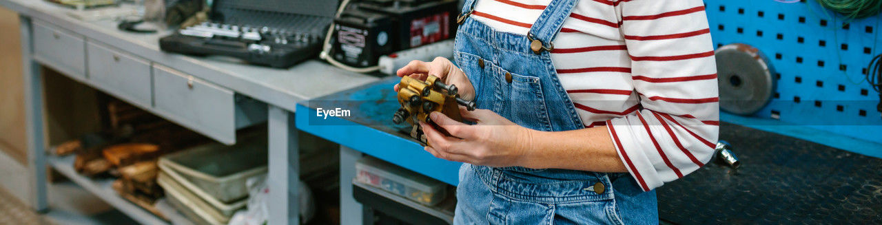 Mechanic woman checking caliper brake system in front of workbench