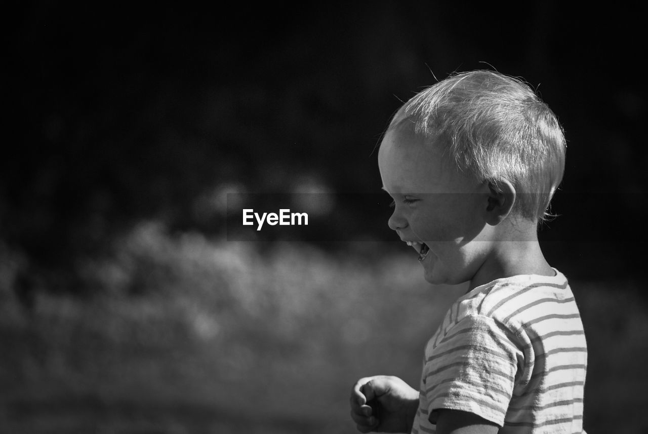 Sunlight falling on boy laughing while looking down