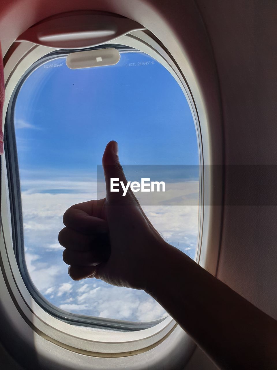 Cropped hand of person gesturing by airplane window