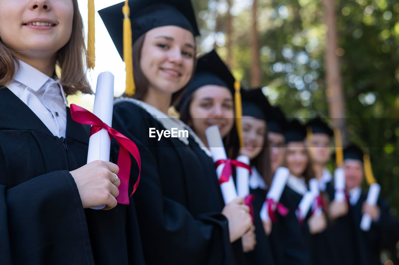 portrait of smiling friends wearing graduation gown