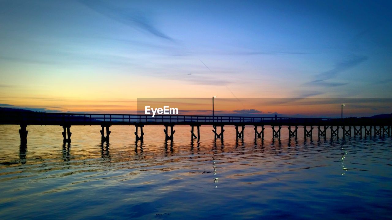 Pier over sea against sky during sunset