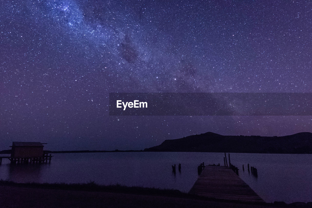 SCENIC VIEW OF LAKE AGAINST MOUNTAIN AT NIGHT