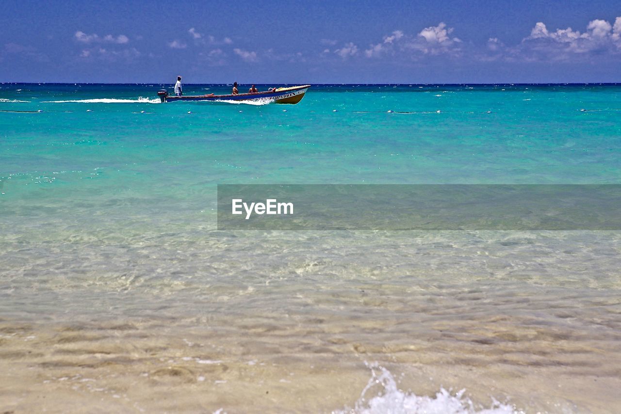 People on boat in sea against sky during sunny day