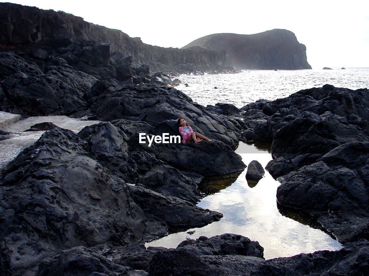 High angle view of girl lying at rocky beach