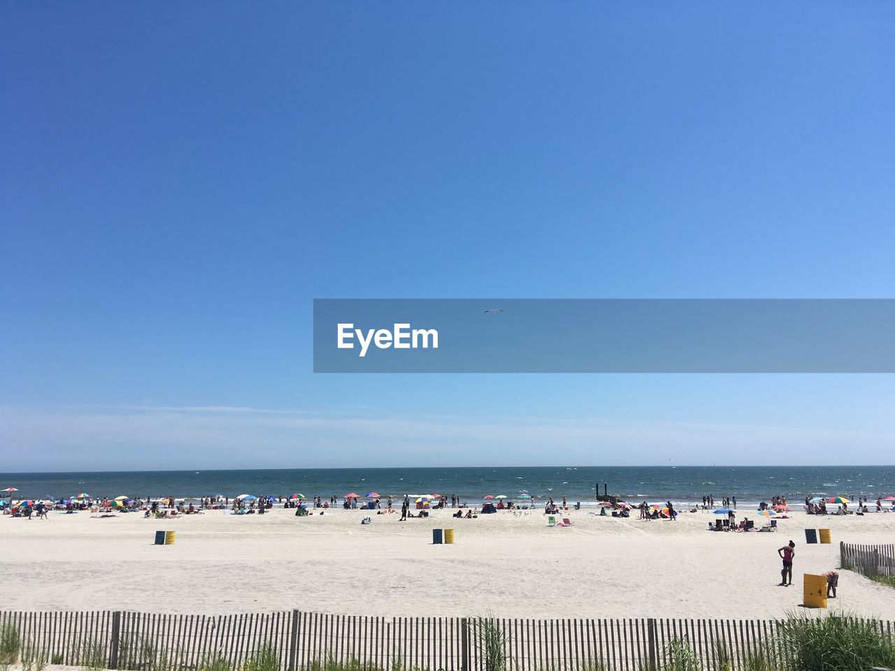 People at beach against clear blue sky