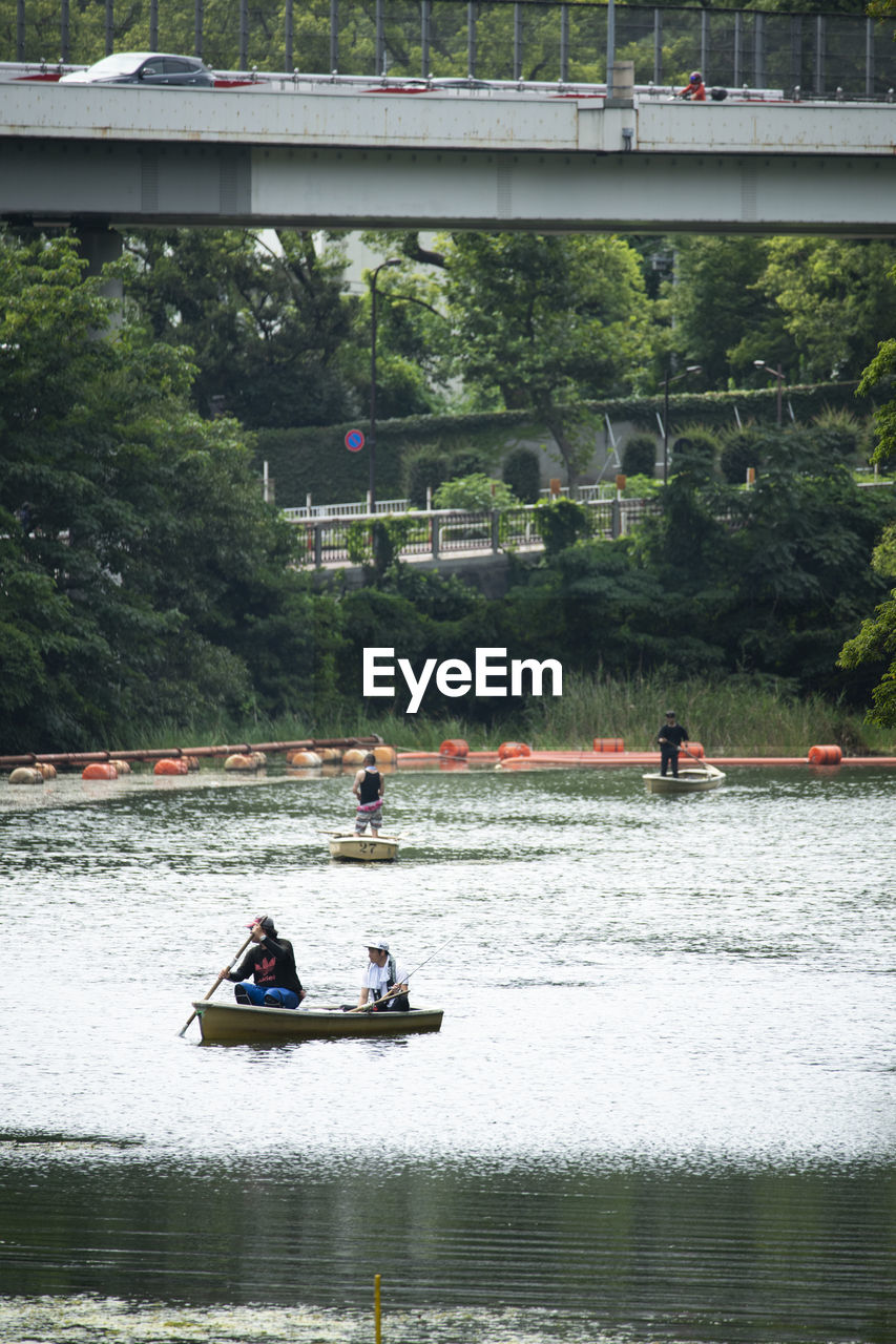 PEOPLE ON RIVERBANK AGAINST TREES