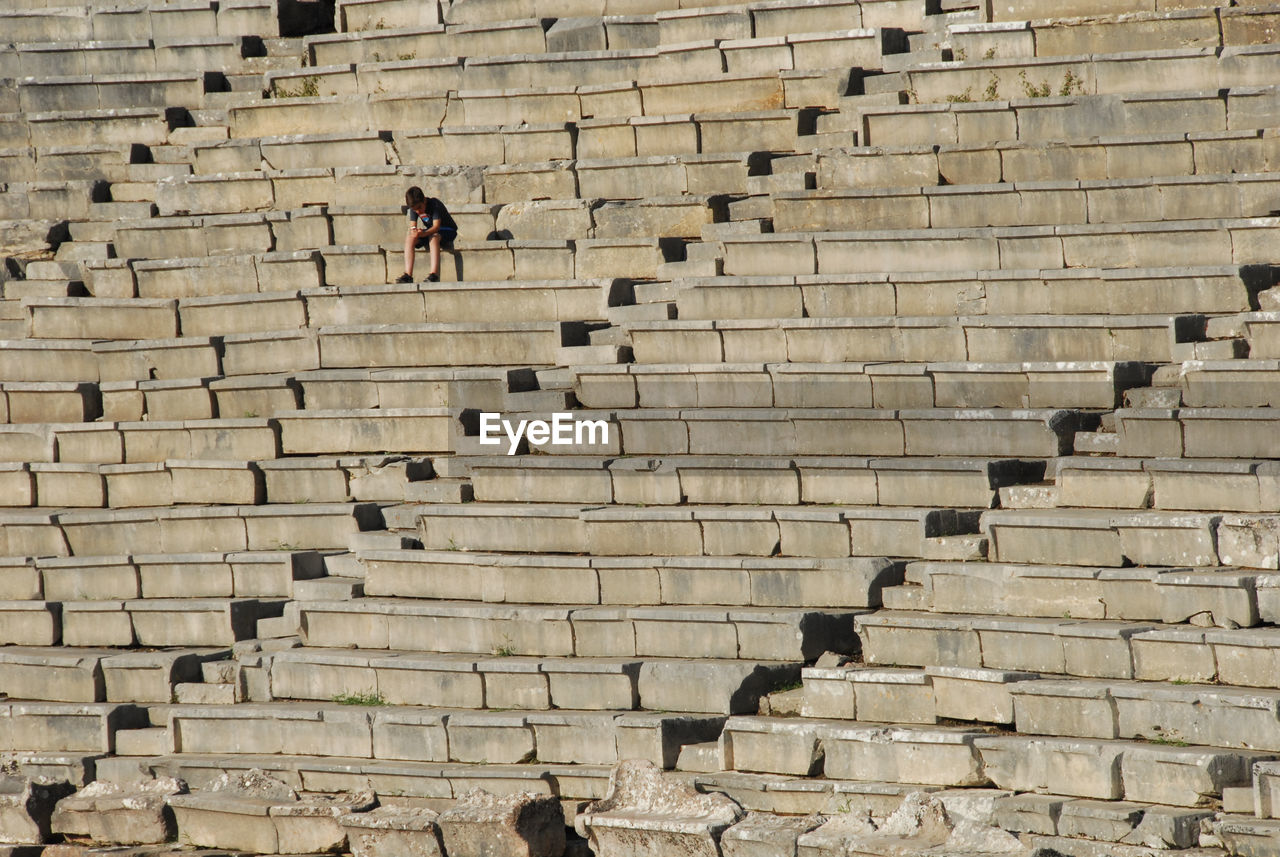 LOW ANGLE VIEW OF MAN WALKING ON STAIRCASE AGAINST WALL