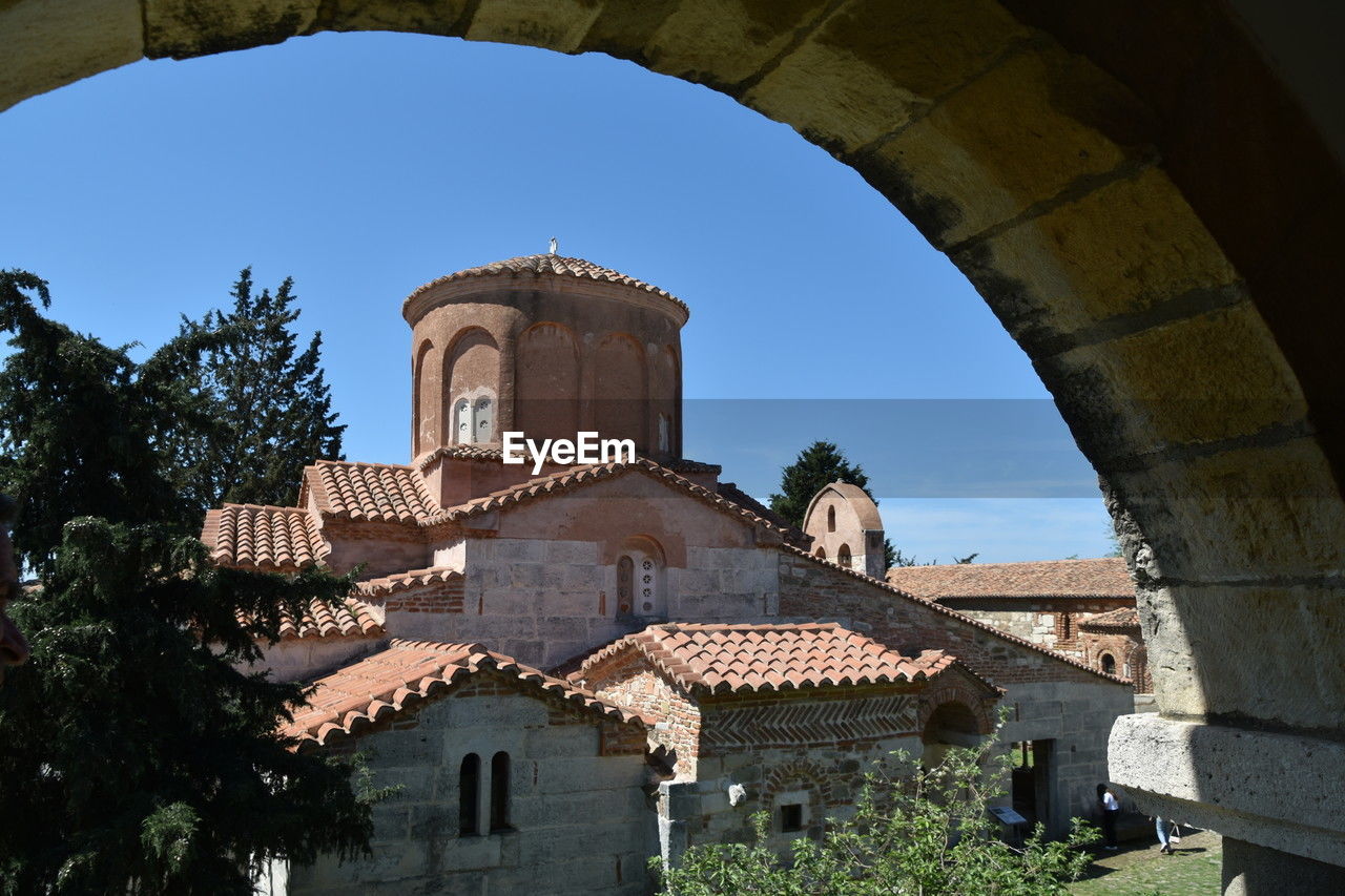 architecture, built structure, building exterior, arch, history, nature, building, the past, plant, landmark, ancient history, travel destinations, tree, sky, no people, religion, travel, place of worship, clear sky, outdoors, tower, belief, day, blue, tourism, old, city, low angle view