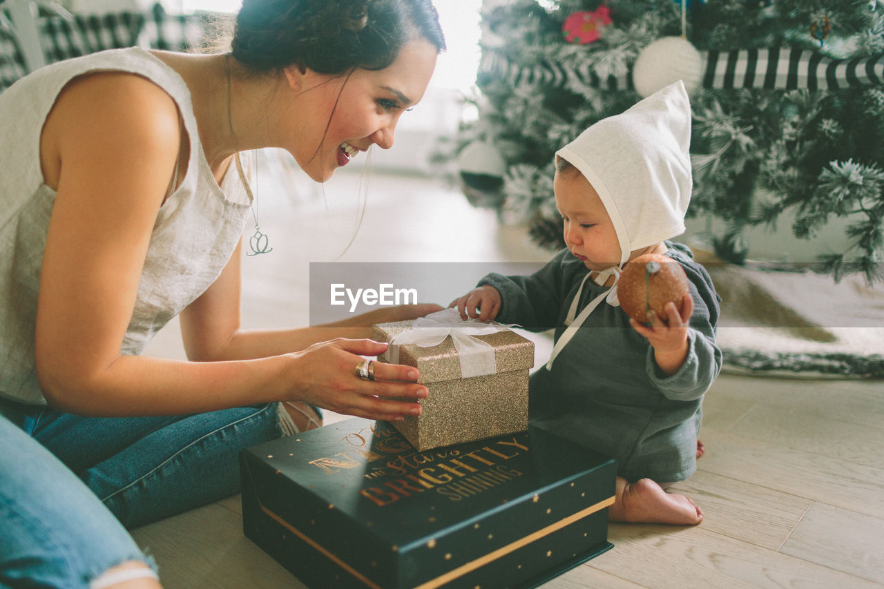 Mother showing christmas present white sitting at home