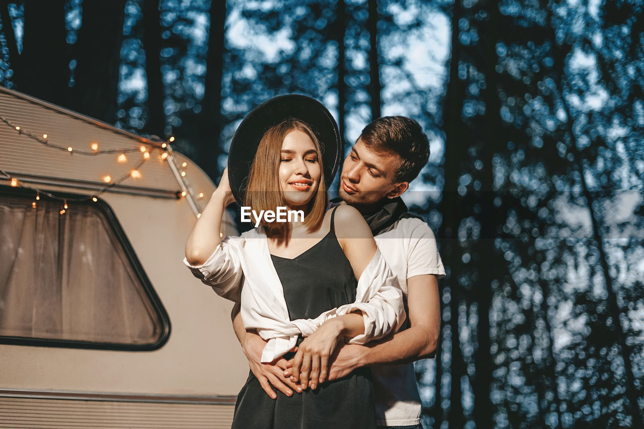 Smiling couple standing against motor home