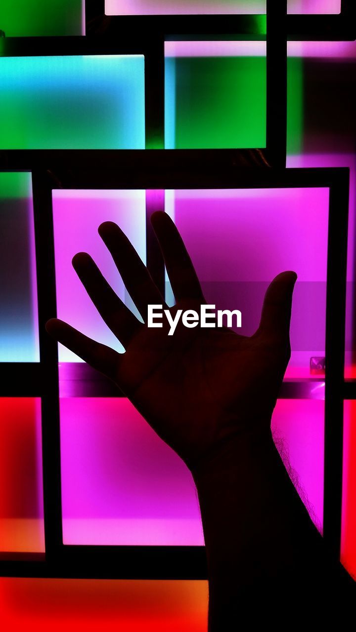 CLOSE-UP OF HUMAN HAND TOUCHING ILLUMINATED LIGHT ON TABLE